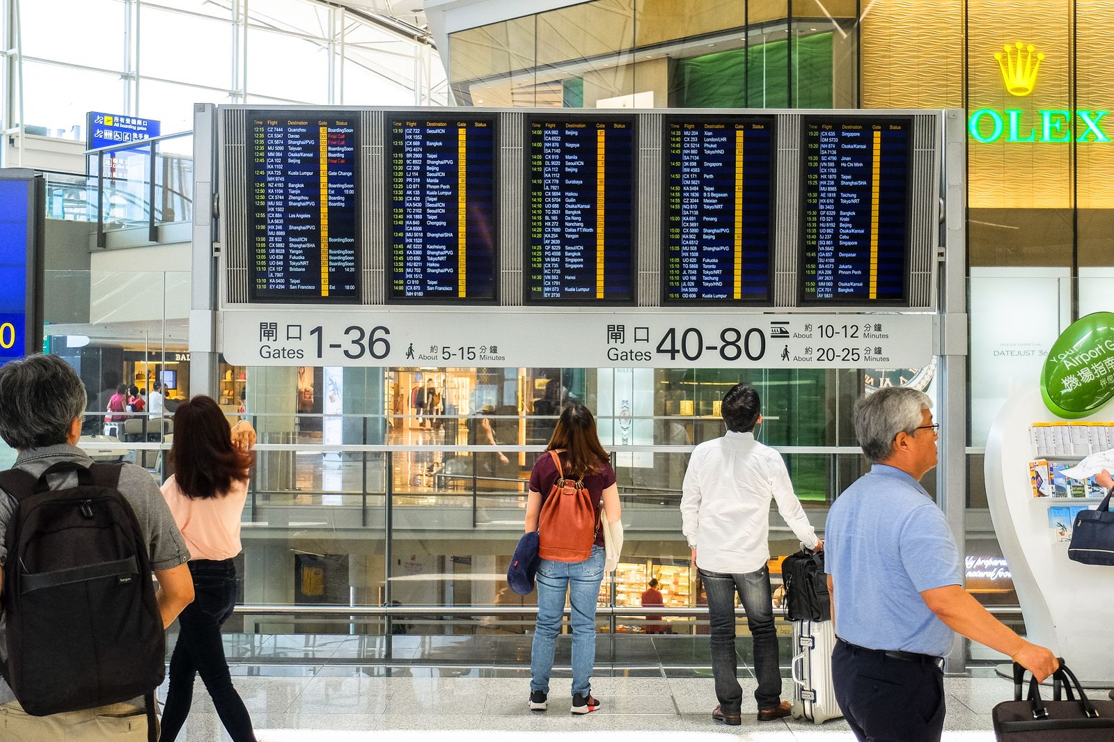 Travellers checking a departures board at the airport